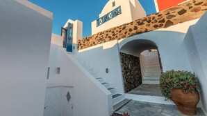 A white building with a stone wall and a blue door.