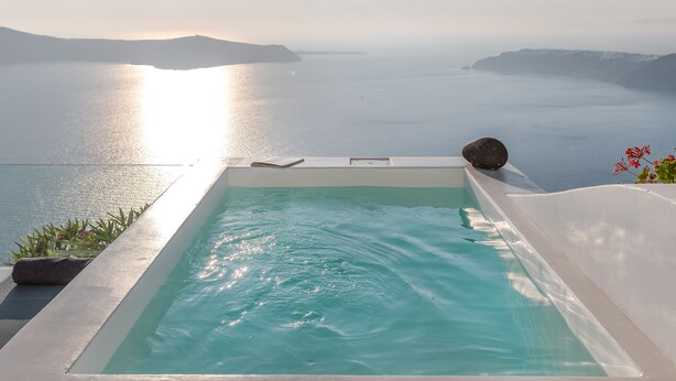 A infinity pool with a view of the sea and distant mountains.