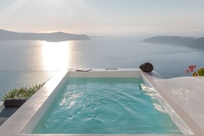 Una piscina infinita con vistas al mar y montañas distantes.