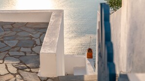 A stone-tiled patio with a white railing overlooking a calm body of water.