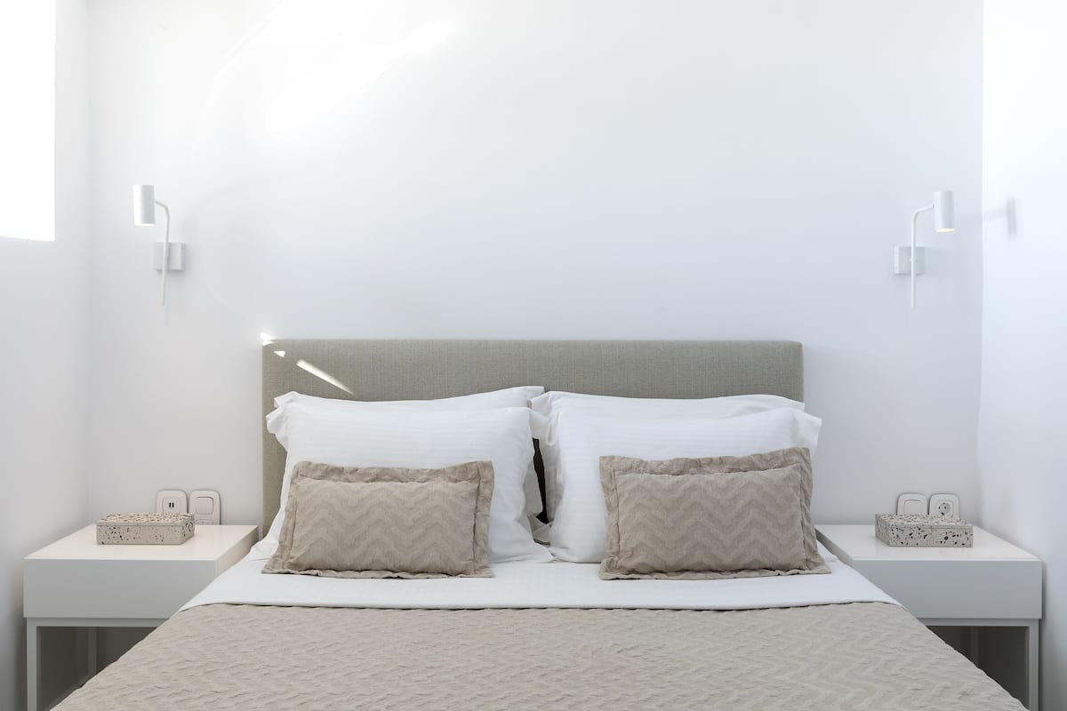 Ein ordentlich eingerichtetes Hotelzimmer mit einem Bett, zwei Nachttischen und Wandleuchten.