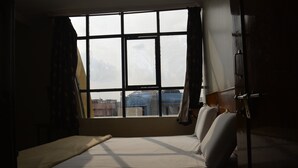 Ein Zimmer mit Bett, Fenster und Blick auf Gebäude.