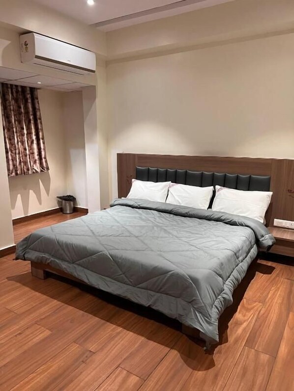 Habitación de hotel moderna con cama, suelo de madera y aire acondicionado de pared.
