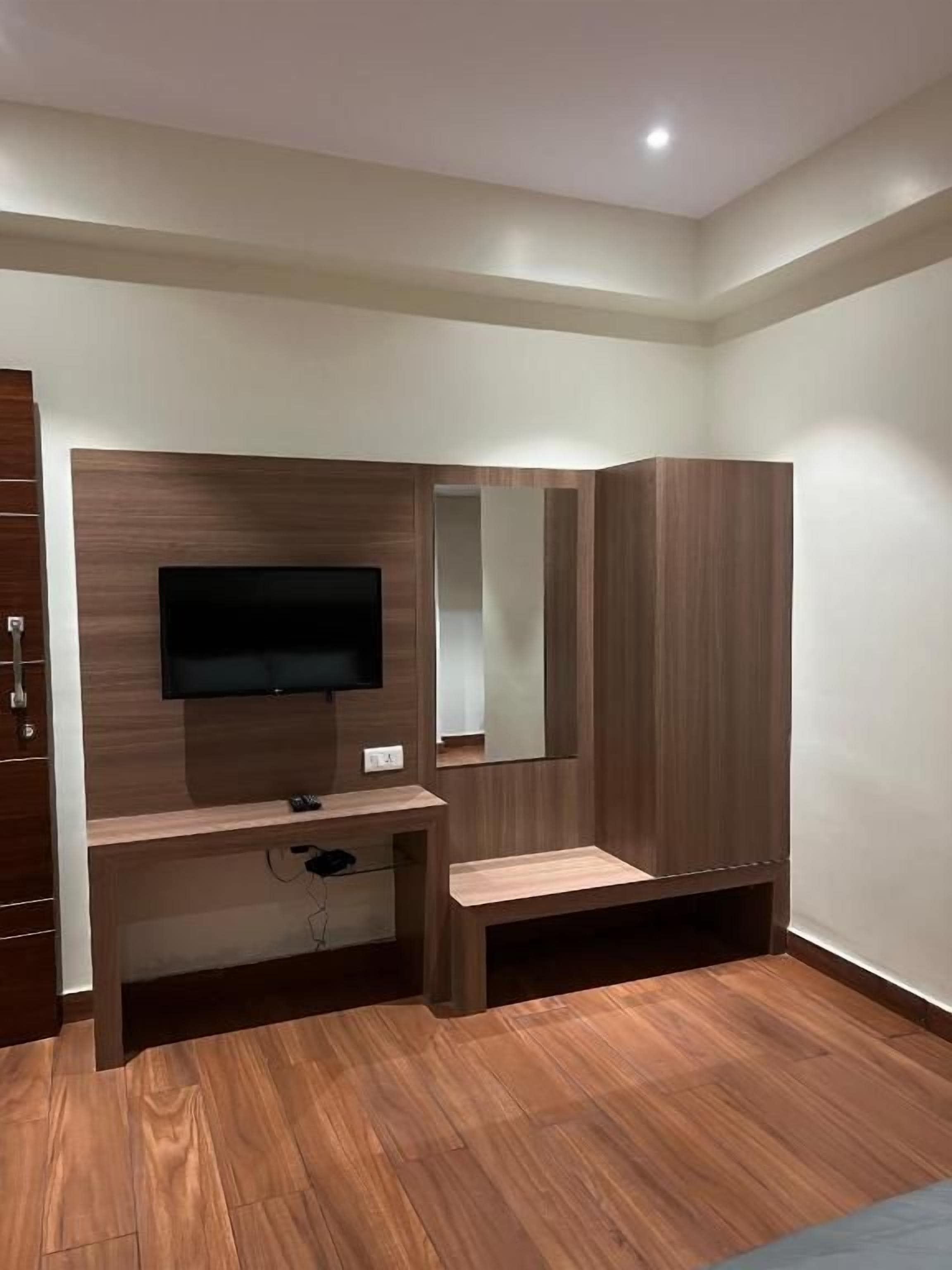 A modern room with a flat-screen TV mounted on a wooden wall, a built-in bench, and a mirror.