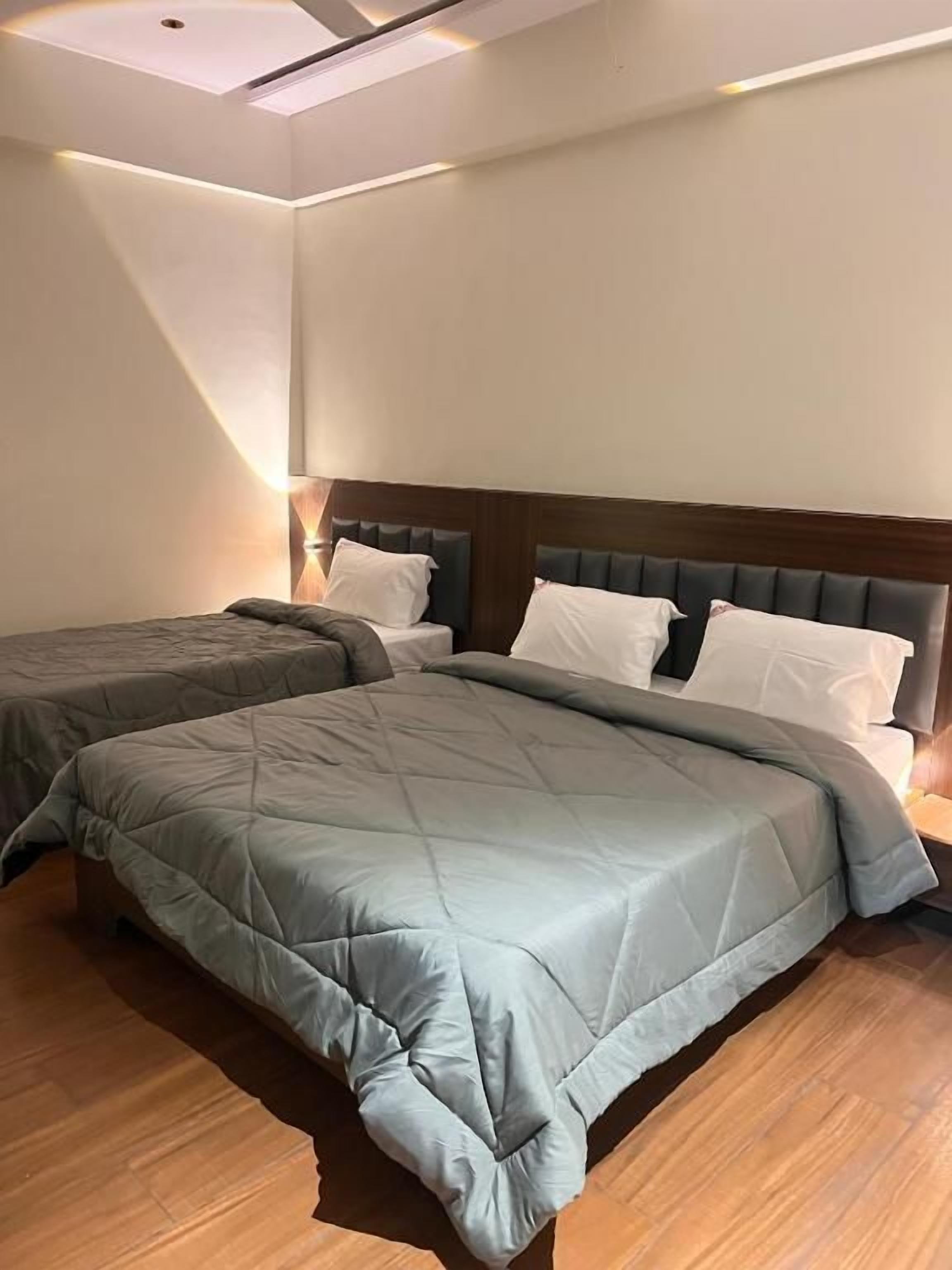A hotel room with two beds, a wooden floor, and a modern headboard.
