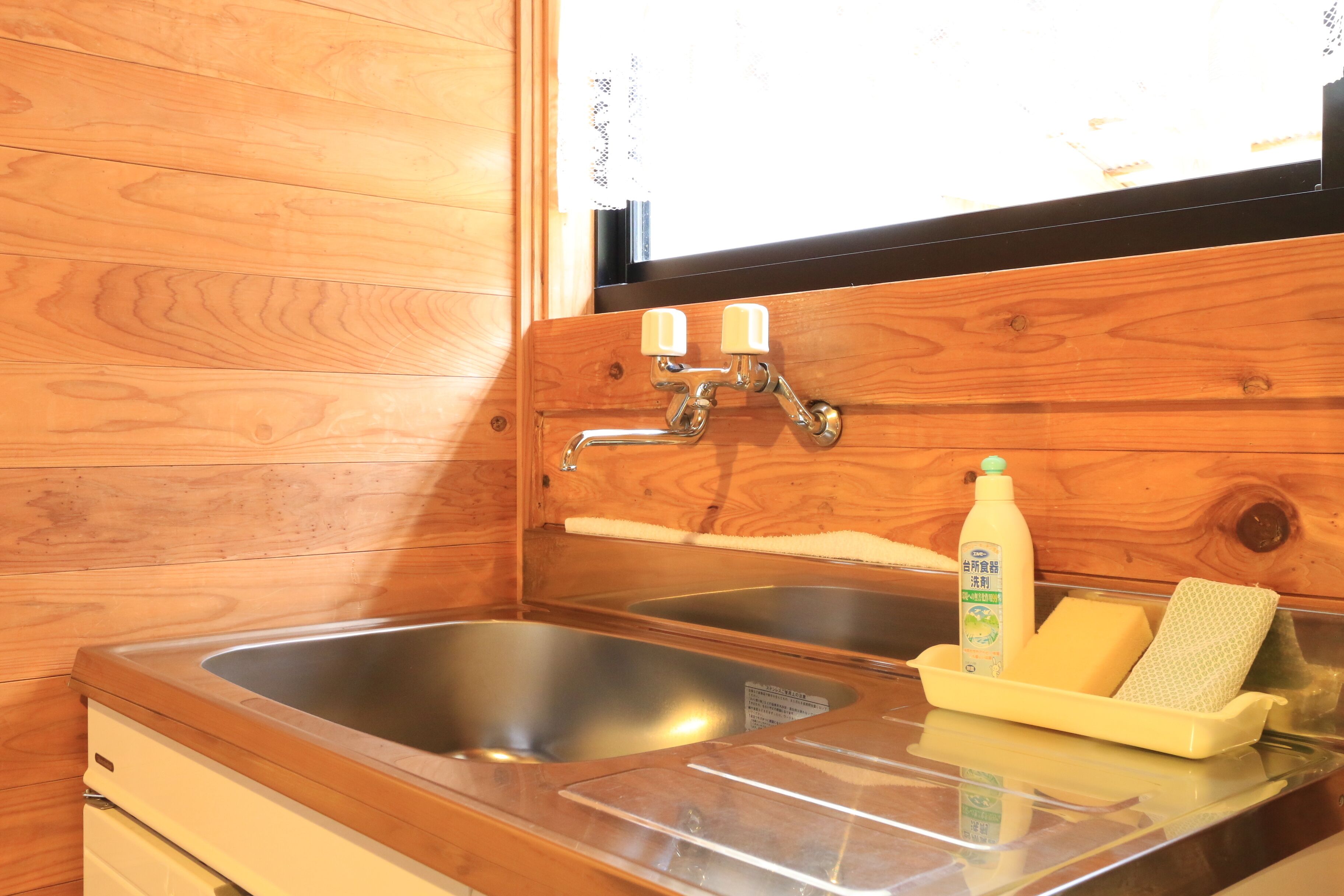 Un baño estilo cabaña de madera con dos lavamanos, una ventana y un jabonera con una esponja.