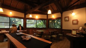 A wooden interior with a long table, chairs, and large windows. - Sen-no-ie (Yakushima)