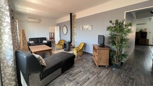 A living room with a sofa, armchair, and a TV stand.