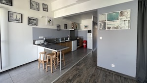 A modern kitchen with a central island, bar stools, and a refrigerator.