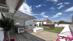 A wooden deck with outdoor furniture, a barbecue area, and a view of the surrounding neighborhood.