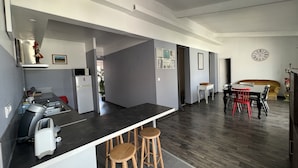 A modern kitchen with a black countertop, wooden stools, and a dining area with a table and chairs.