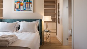 Una habitación de hotel con cama, lámpara, un cuadro y armario.
