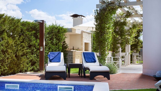 Un área de piscina con sillas de descanso y una pérgola.