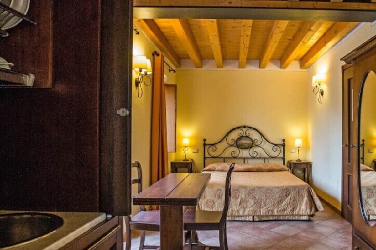 Une chambre à coucher comprenant un lit, des tables de chevet, une chaise en bois et une armoire en bois.