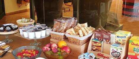 En buffet med forskellige retter, herunder frugt, brød og pakker med snacks.