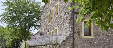 A stone building with multiple windows and a paved pathway leading to it.