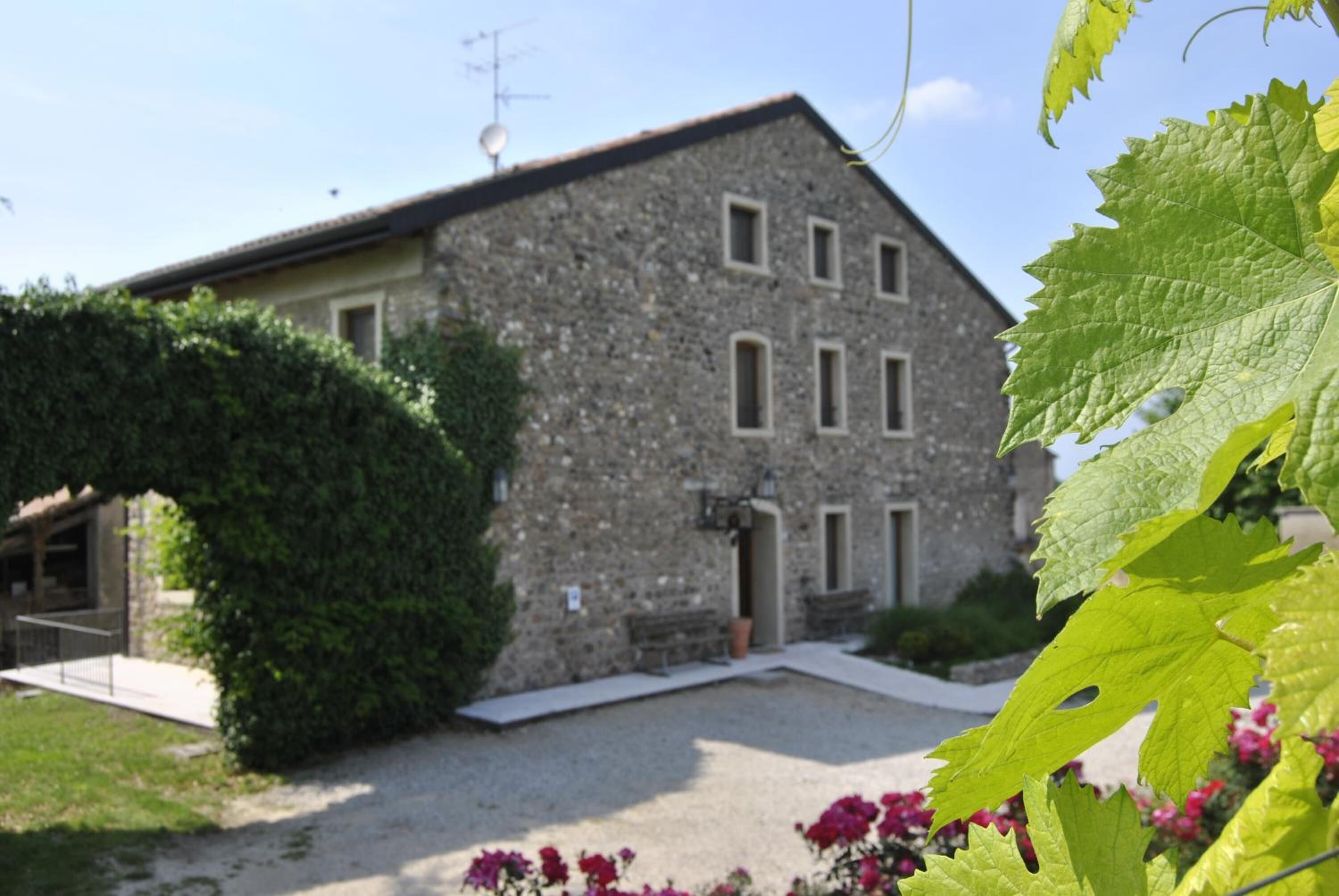 A stone building with a gravel driveway and a bench.