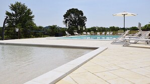 Un espace piscine offrant une vue dégagée sur la piscine, des chaises longues et des parasols.