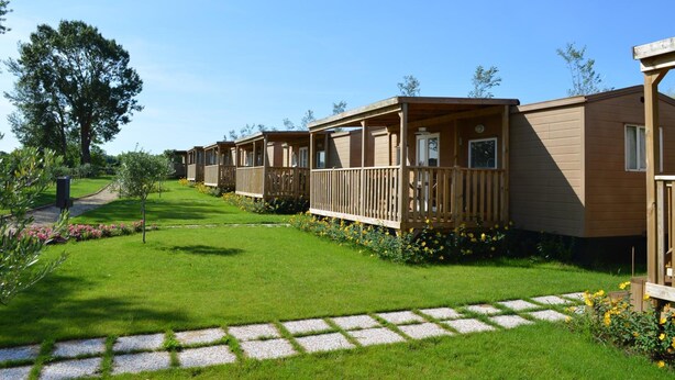 Une rangée de chalets en bois dotés de balcons, une pelouse bien entretenue et un ciel dégagé.