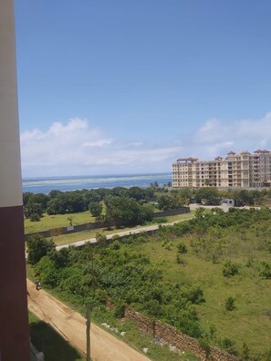 A view of a residential area with a large building complex and a dirt road leading to it. - Alpha House (Mombasa)