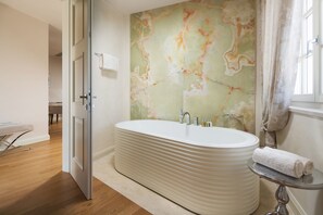 A modern bathroom with a freestanding bathtub, a marble wall, and a small table with a towel. - Villa Cesara (Tar-Vabriga)