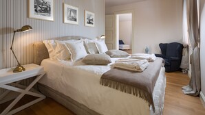 Un dormitorio ordenado con cama, mesitas de noche y una silla.
