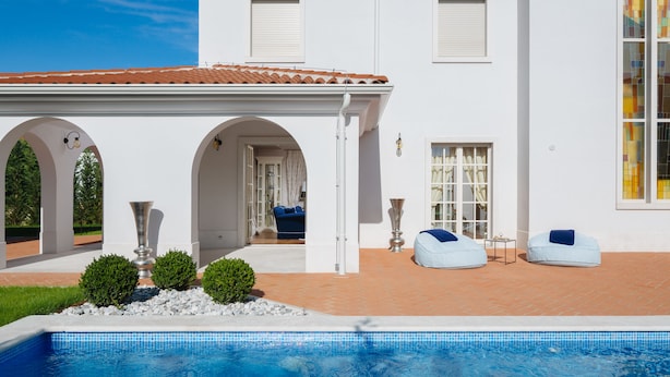 Un edificio blanco con piscina, arcos y zona de estar al aire libre.