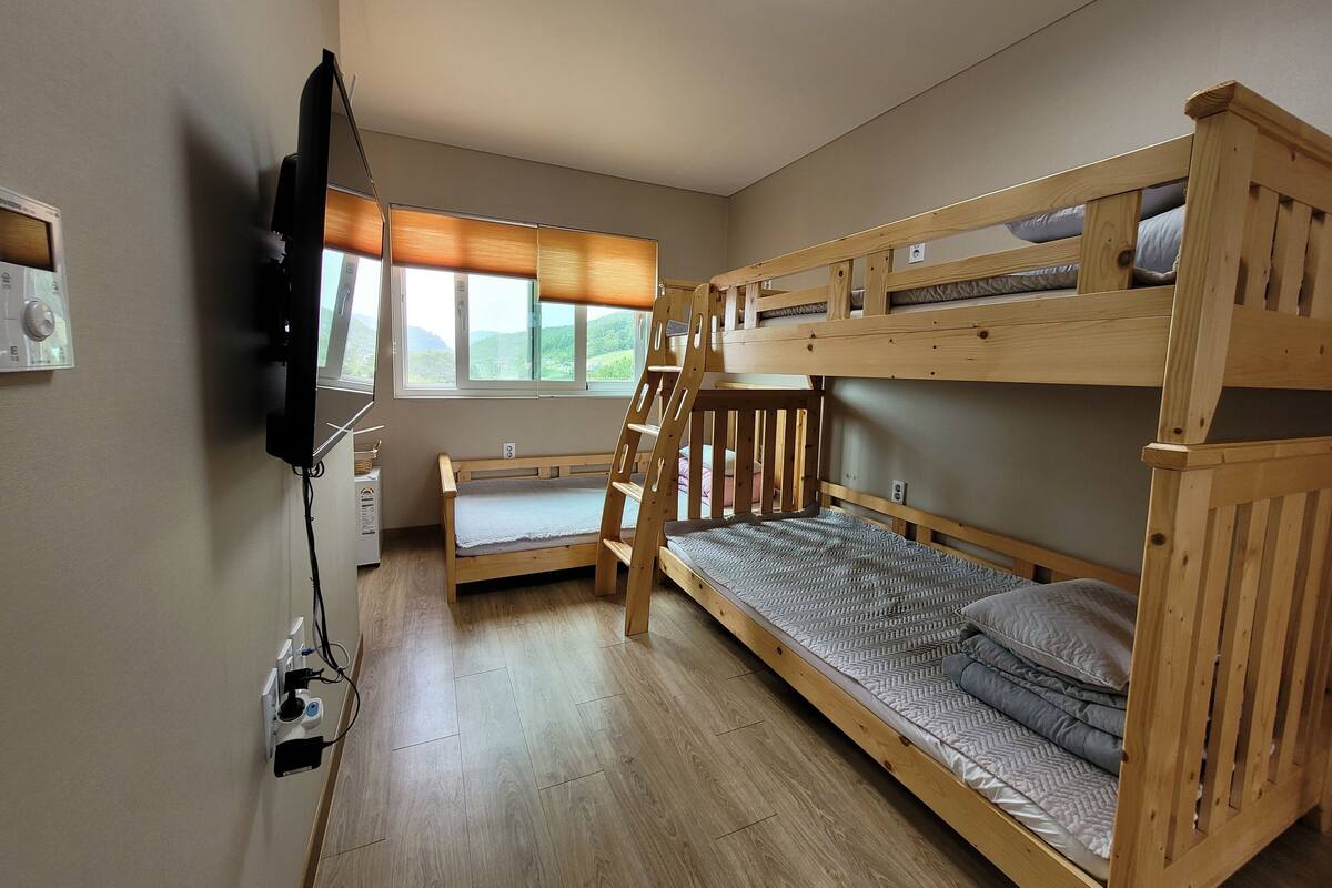 Habitación con literas, televisión, escritorio y ventana con vistas al exterior.