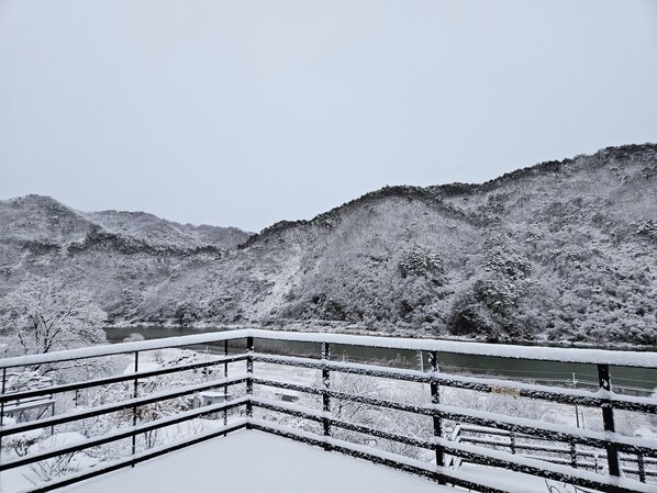 Paisaje nevado con un río y montañas al fondo.