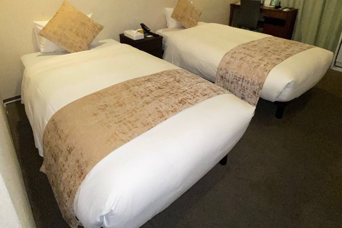 Ein Hotelzimmer mit zwei Betten, einem Schreibtisch und einem Stuhl.