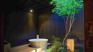 Ein Whirlpool in einer Holzhütte mit kleinem Garten und einer Holzterrasse.