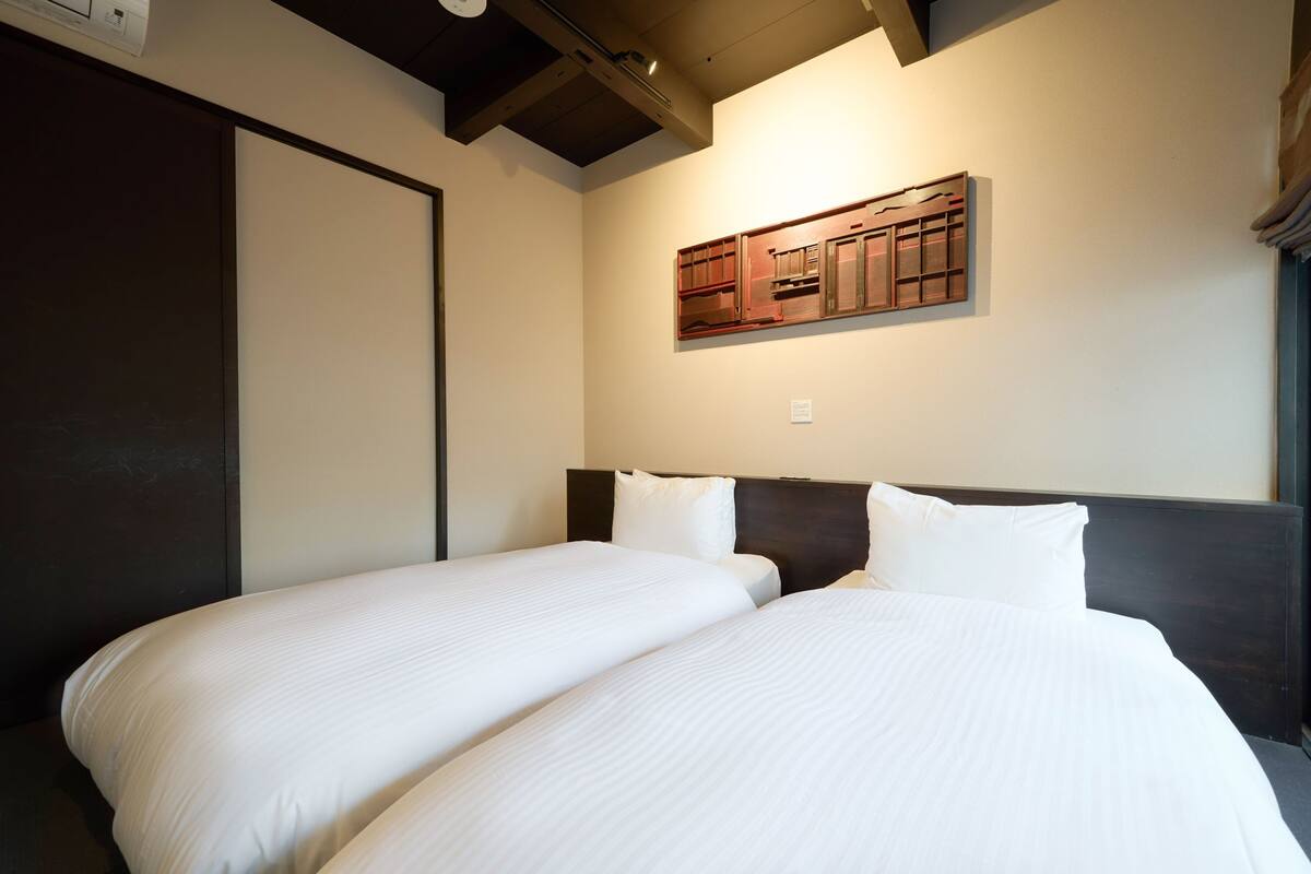 A hotel room with two beds, a wooden headboard, and a wall-mounted cabinet.