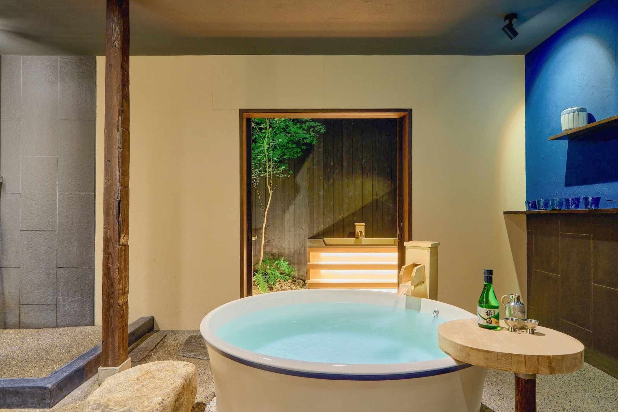 Uma área de spa com hidromassagem, uma mesa de madeira com garrafas e vista para uma escada que leva a um deck de madeira.