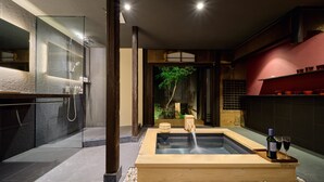 Ein modernes Badezimmer mit einer gläsernen Duschkabine, einer Holzbadewanne und einer kleinen Innenraumbepflanzung.