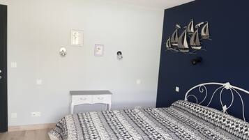 Een slaapkamer met een bed, nachtkastje, kapstok en decoratieve wanddecoratie.