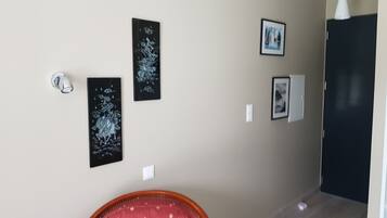 Un couloir avec une porte, un interrupteur et trois œuvres d’art encadrées accrochées au mur.