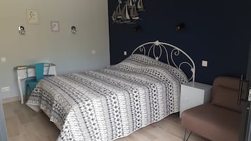 Un dormitori amb llit, escriptori, cadira i armari.