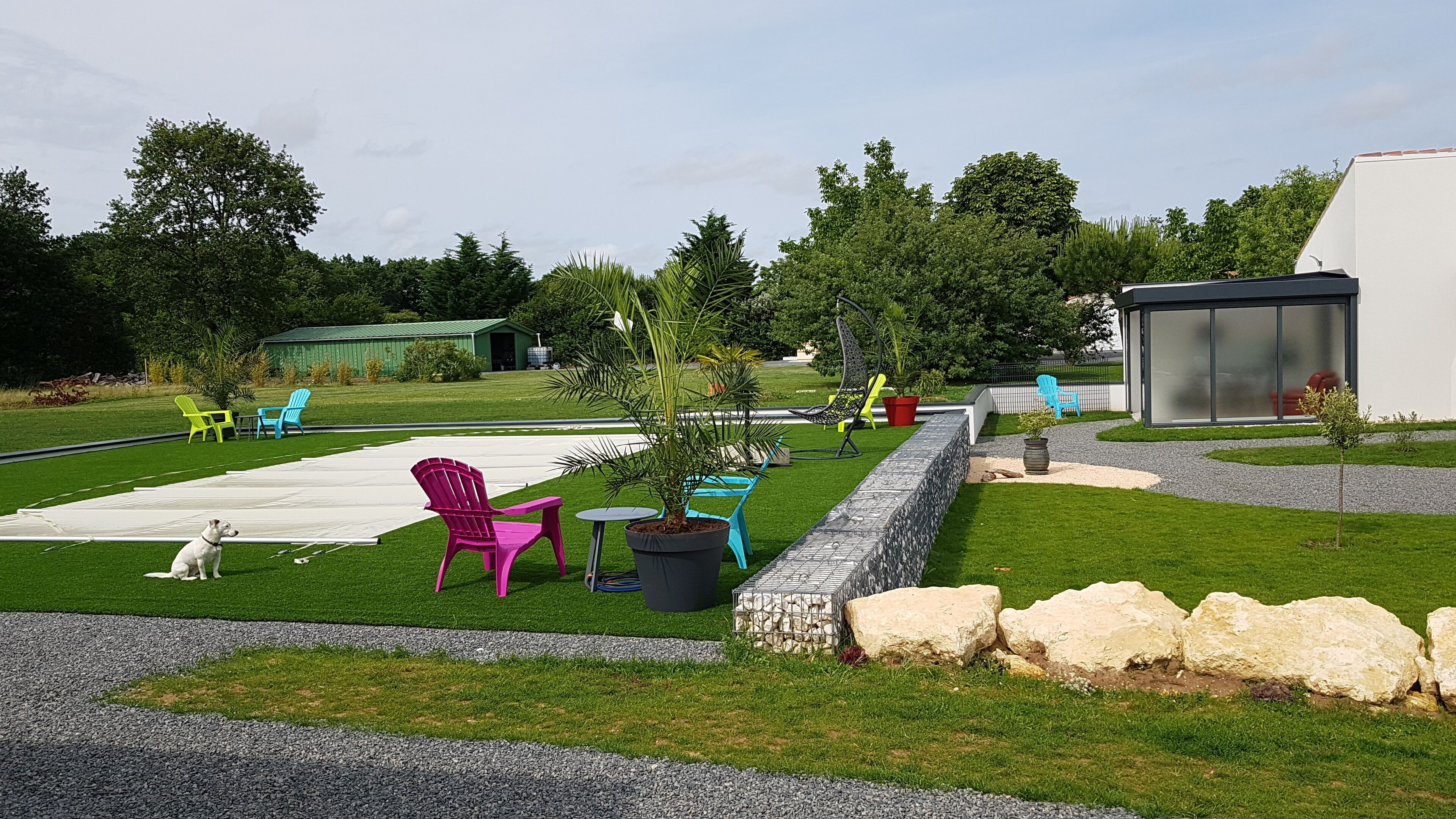 Un espace extérieur bien entretenu, comprenant une pelouse, des aménagements pour s’asseoir et une petite construction.