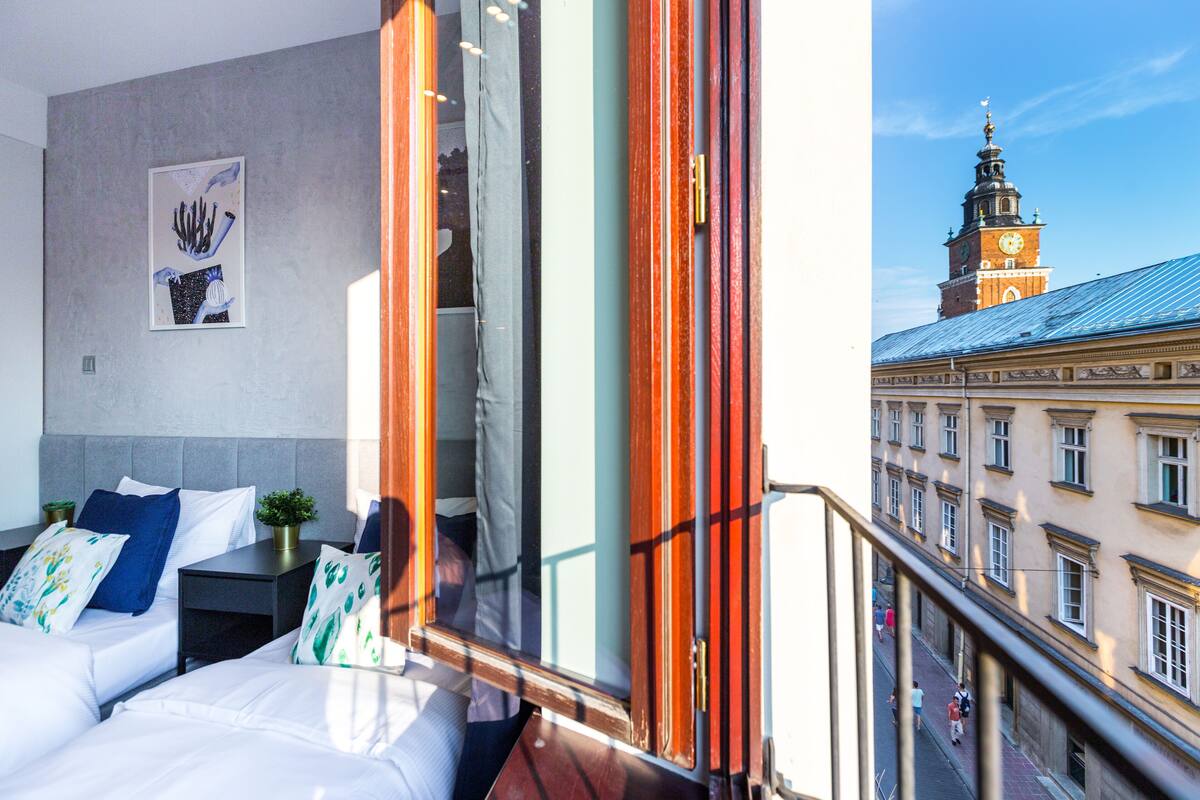 A hotel room with a bed, bedside tables, and a view of a historic building with a clock tower.