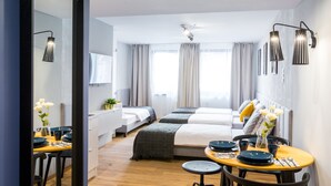 Ein modernes Hotelzimmer mit Holzboden, einer Essecke mit rundem Tisch und Stühlen, einem großen Spiegel und einem Bett mit Kopfteil.