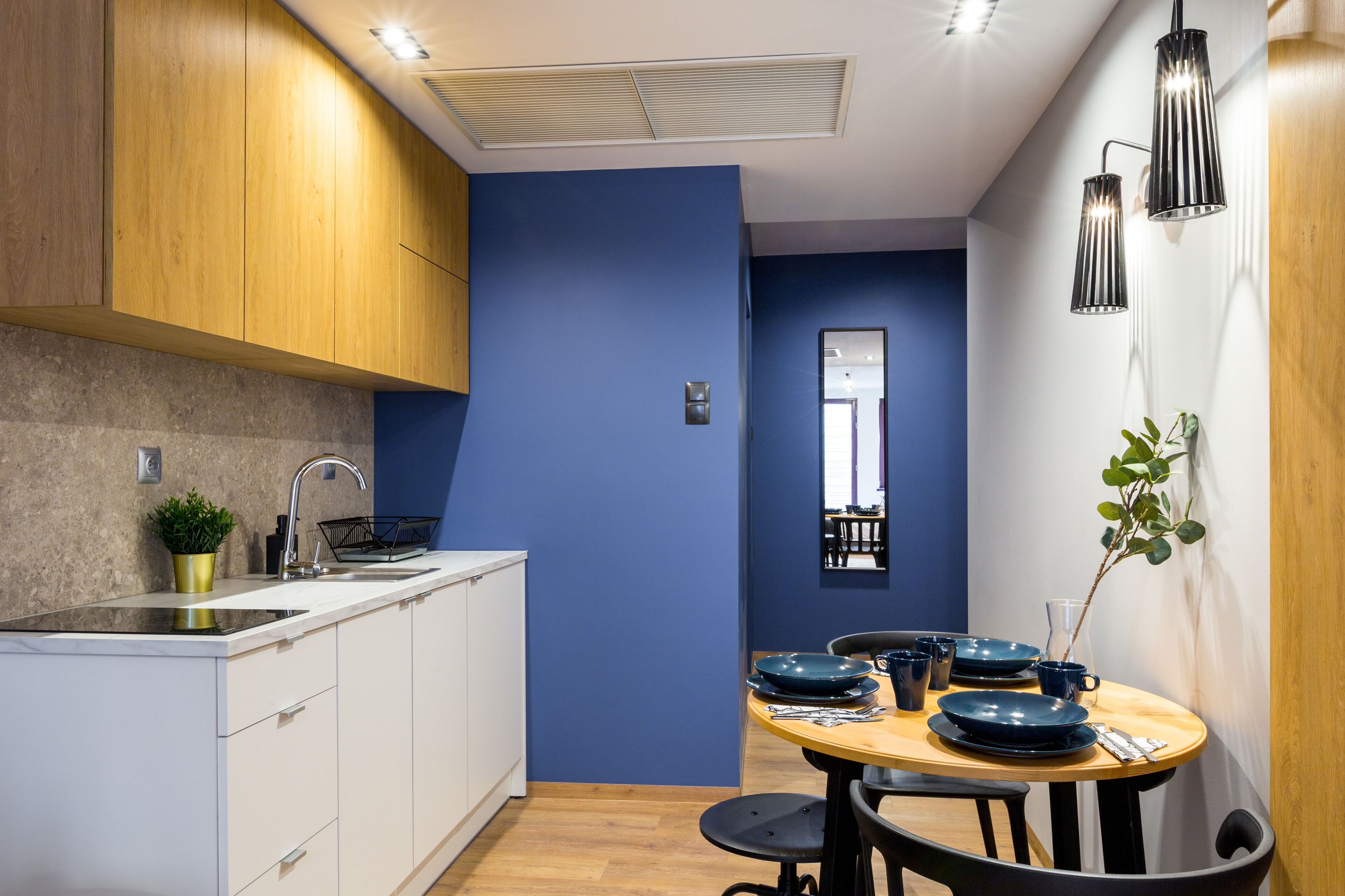 Una cocina moderna con armarios blancos, encimera de madera y una pared decorada en azul.