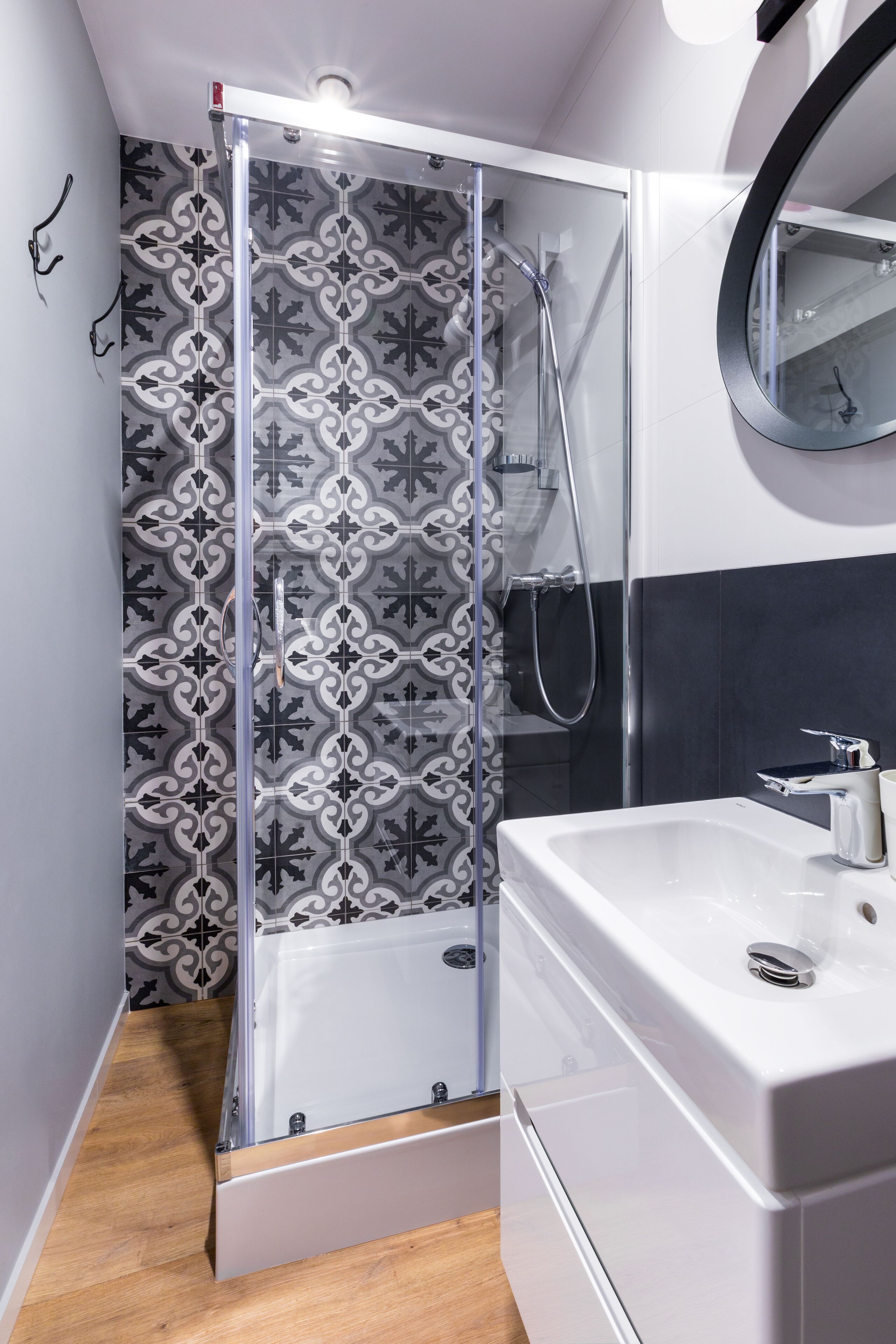A modern bathroom with a glass-enclosed shower, a white sink, and a mirror.