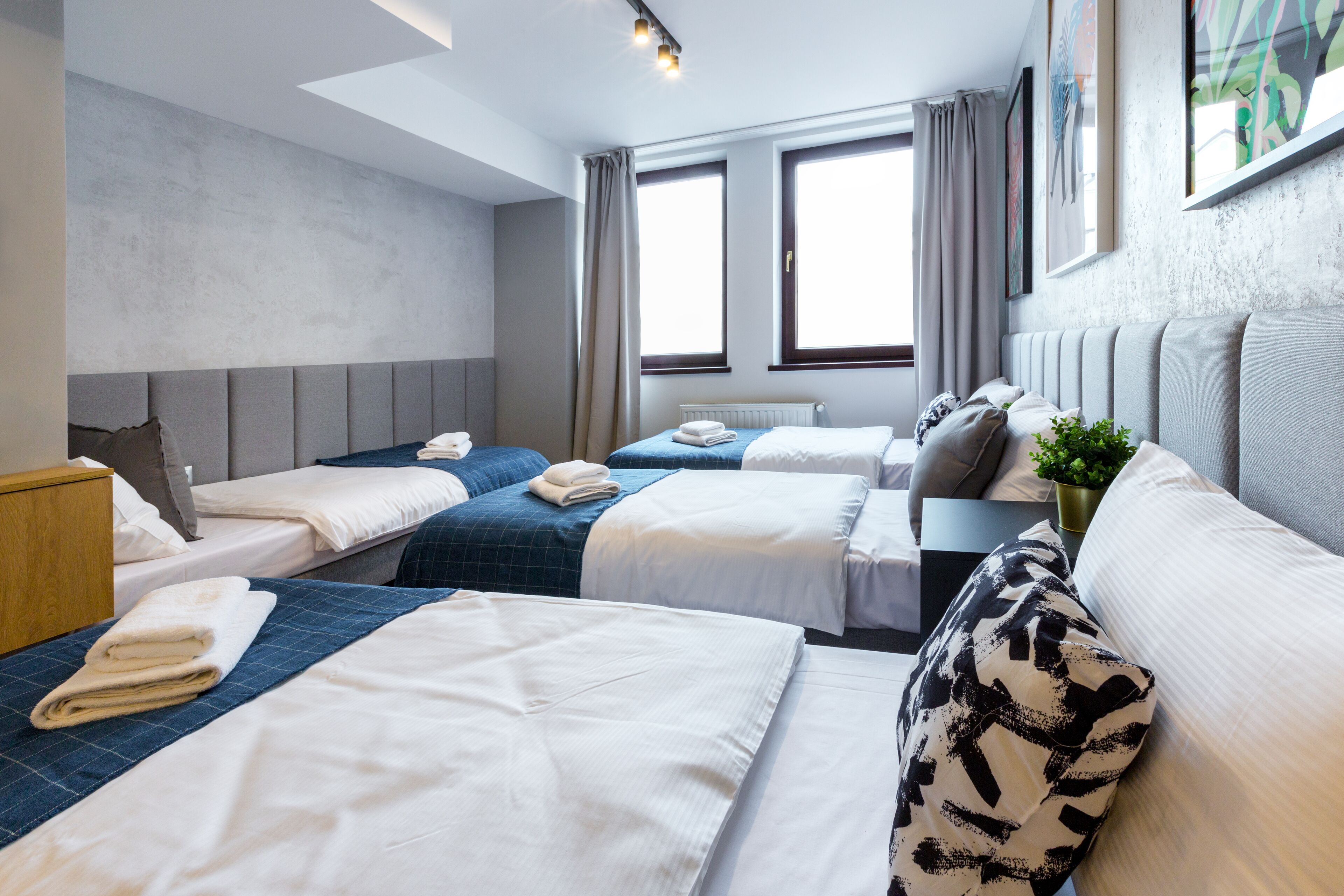 A hotel room with two beds, a sofa, a small table, and a window with curtains.
