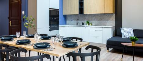 A modern kitchen with white cabinets, a wooden countertop, and a dining area with a wooden table and black chairs.