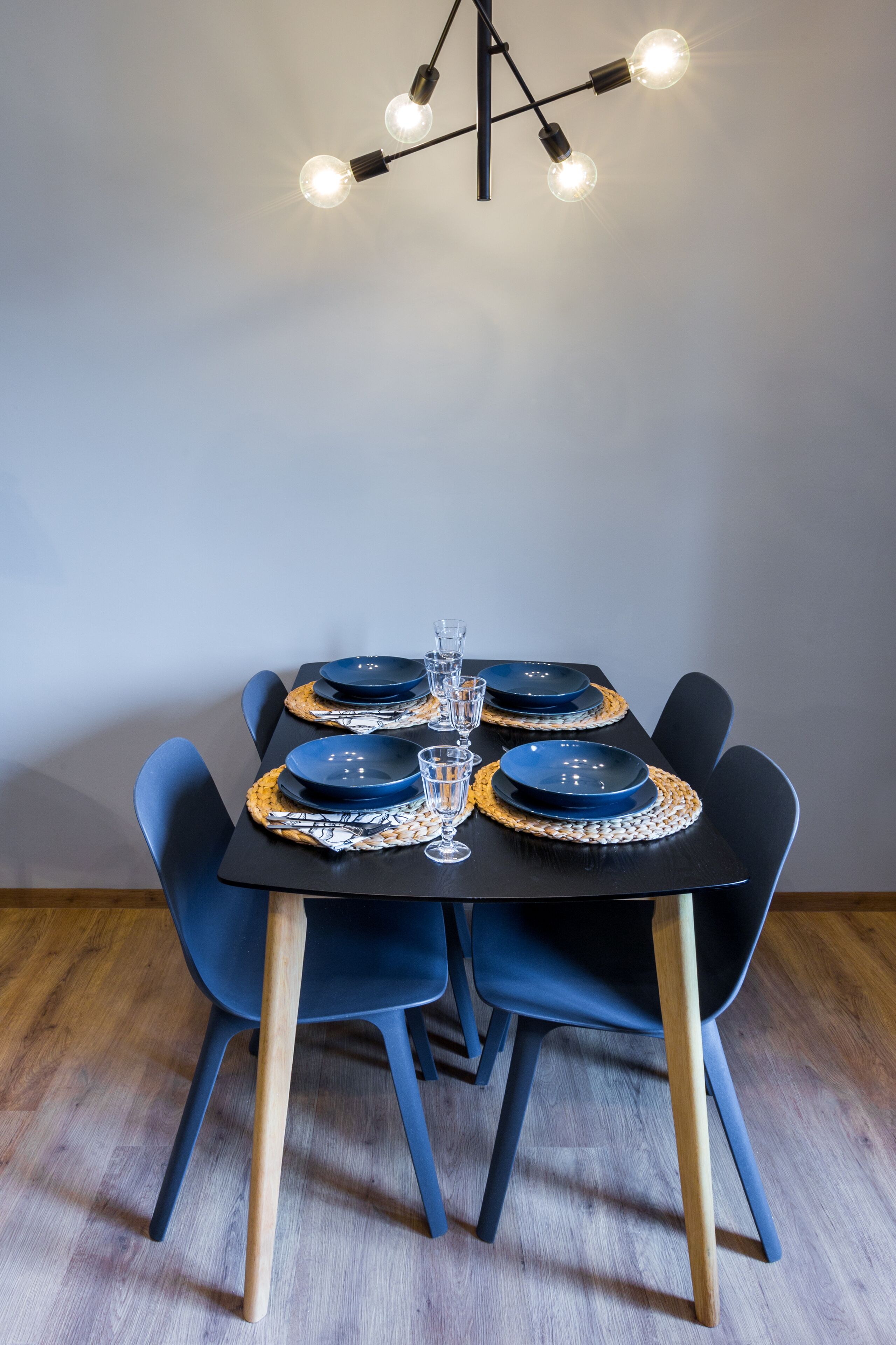 Ett matbord dukat med blå tallrikar, ett glas och en trästol.
