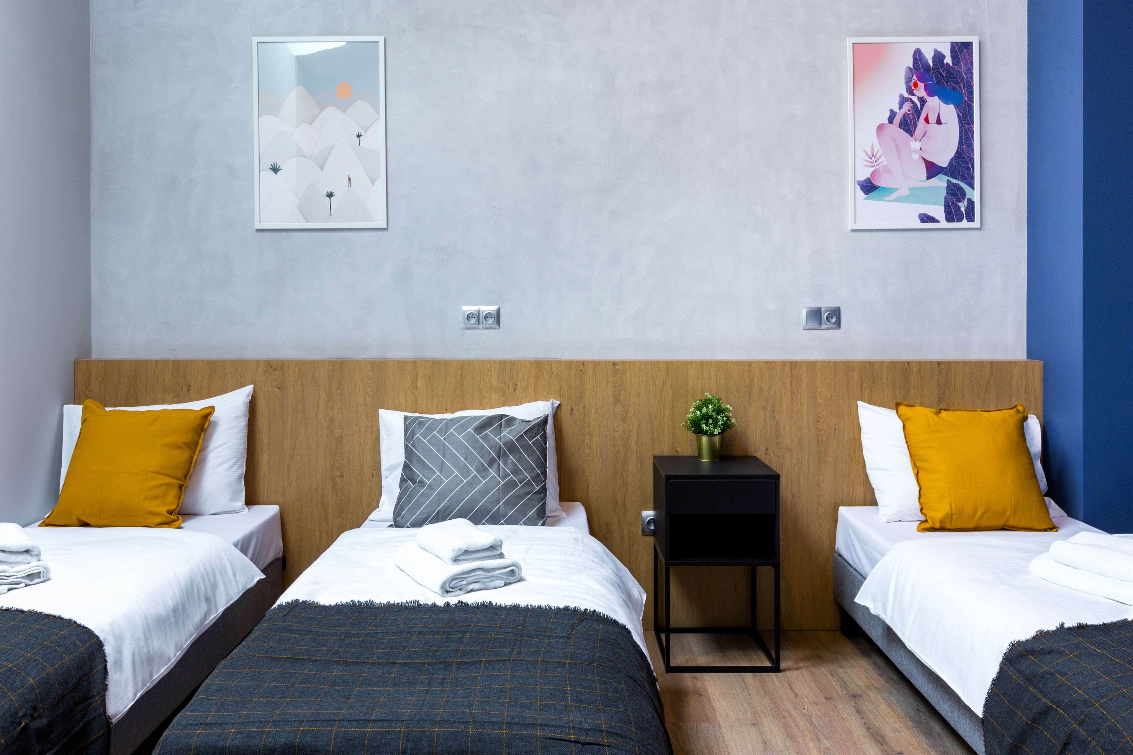 Une chambre d’hôtel avec deux lits, une tête de lit en bois et deux œuvres d’art encadrées accrochées au mur.