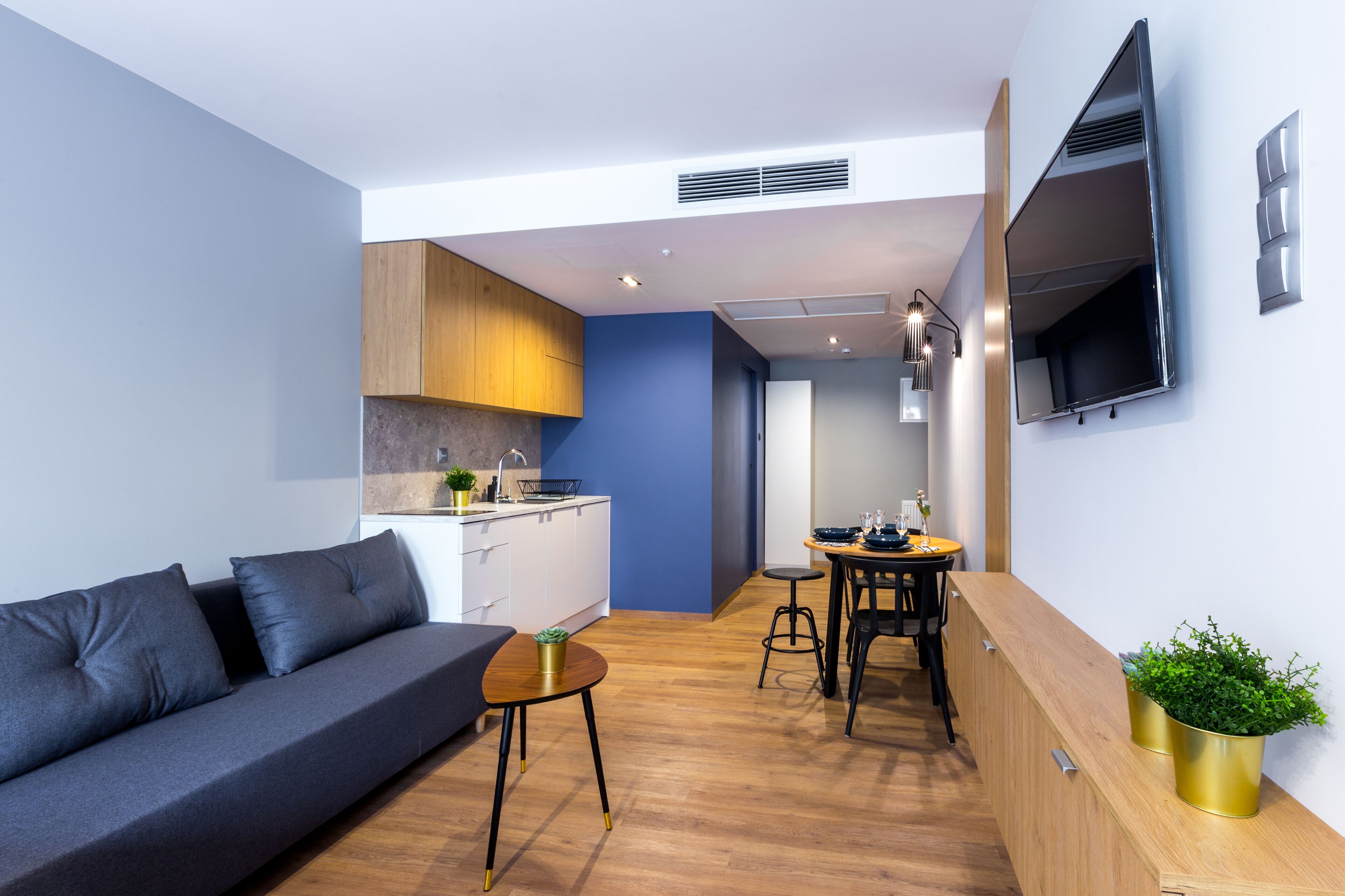 A modern living space with a sofa, dining table, and kitchen area.