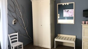 Une pièce comprenant une armoire, un banc, une chaise, un téléviseur fixé au mur et une branche décorative accrochée au mur.