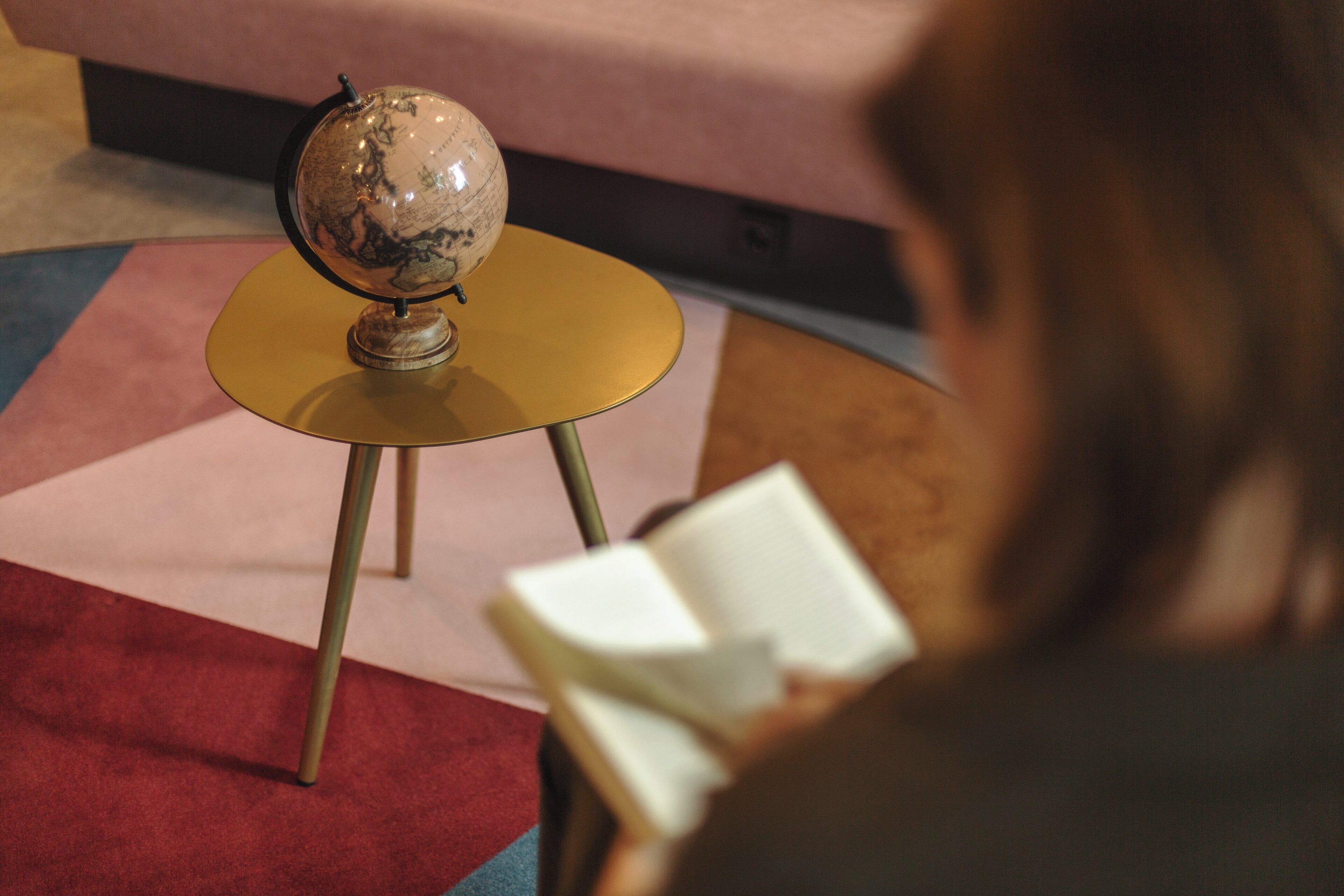 Een wereldbol op een bijzettafeltje, met een boek op de voorgrond.