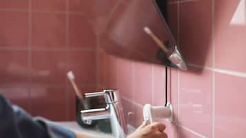 Una mano ajustando un dispensador de toallas fijado en una pared de azulejos.